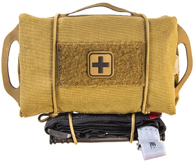 An IFAK bag seen from the outside. It's tan and has a first aid cross on it. At the bottom a tourniquet is attached with rubber ties.