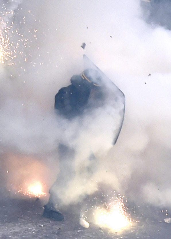 Cover of War in the Streets. Shows either a cop or well prepared activist with a helmet and shield engulfed in tear gas or smoke.