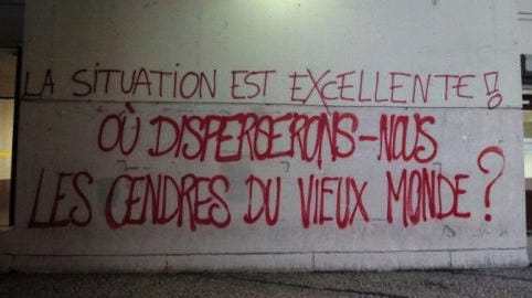 Red graffiti on concrete reads "The situation is excellent --- where shall we toss the ashes of the old world?" in French.